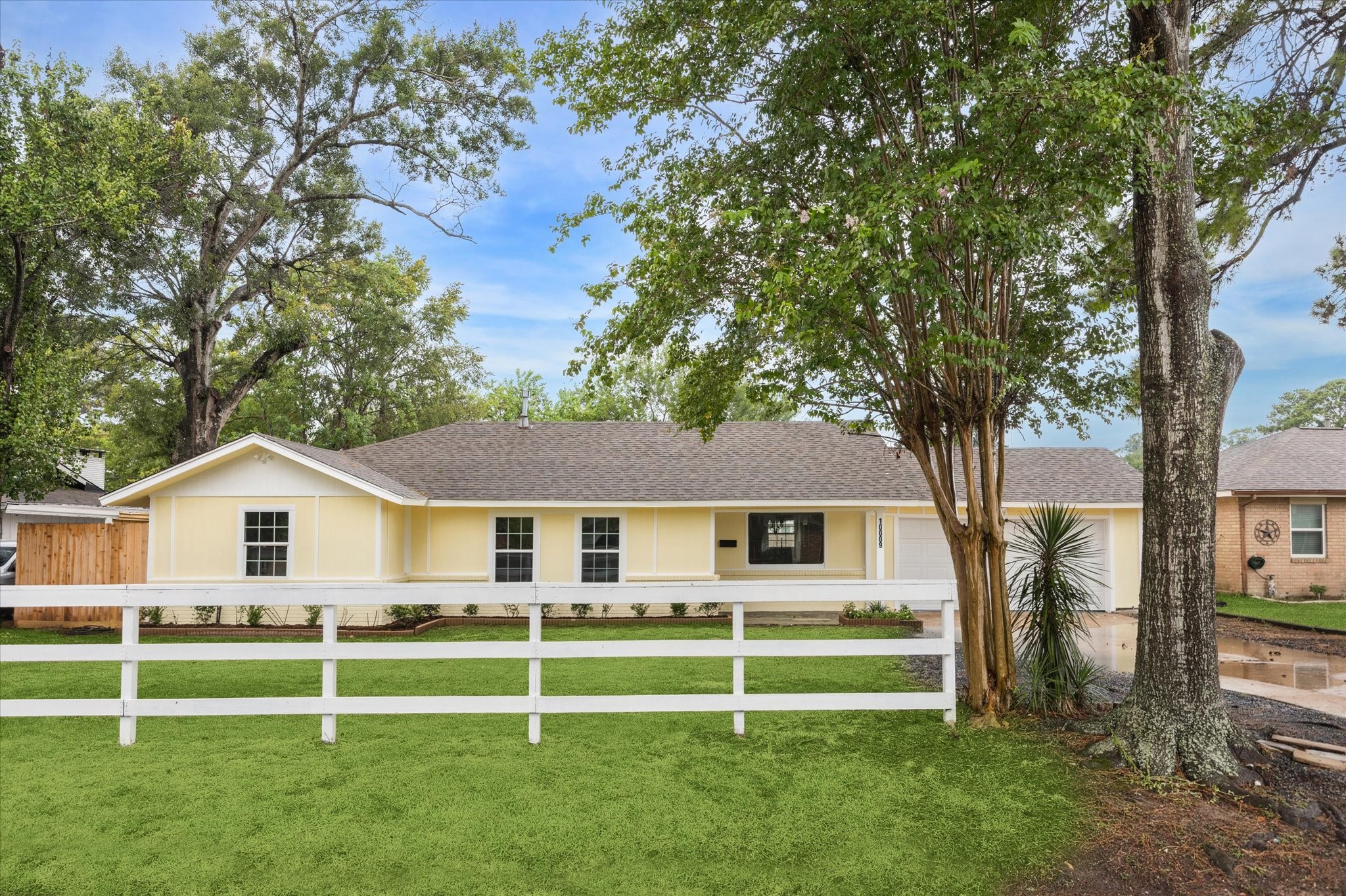 a view of a white house with a big yard and large trees