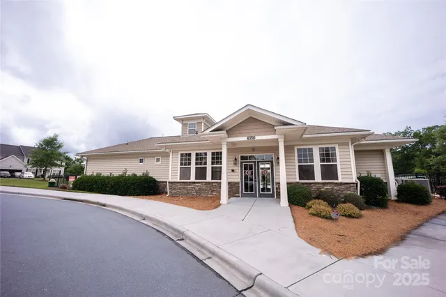 a view of a white house next to a yard with potted plants