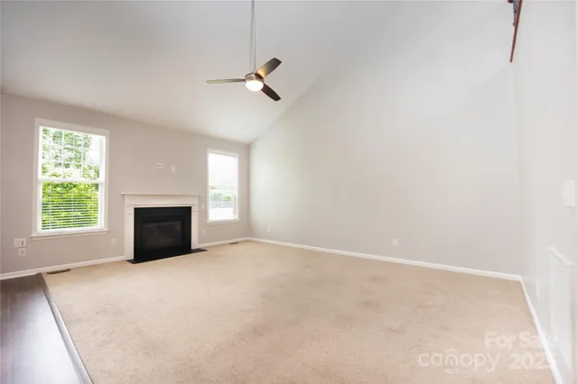 an empty room with windows and fireplace