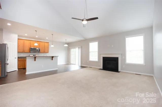 a view of an empty room with a kitchen and a window