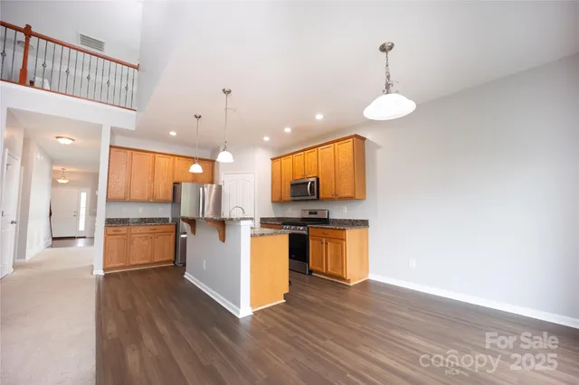 a large kitchen with a center island wooden floor and stainless steel appliances