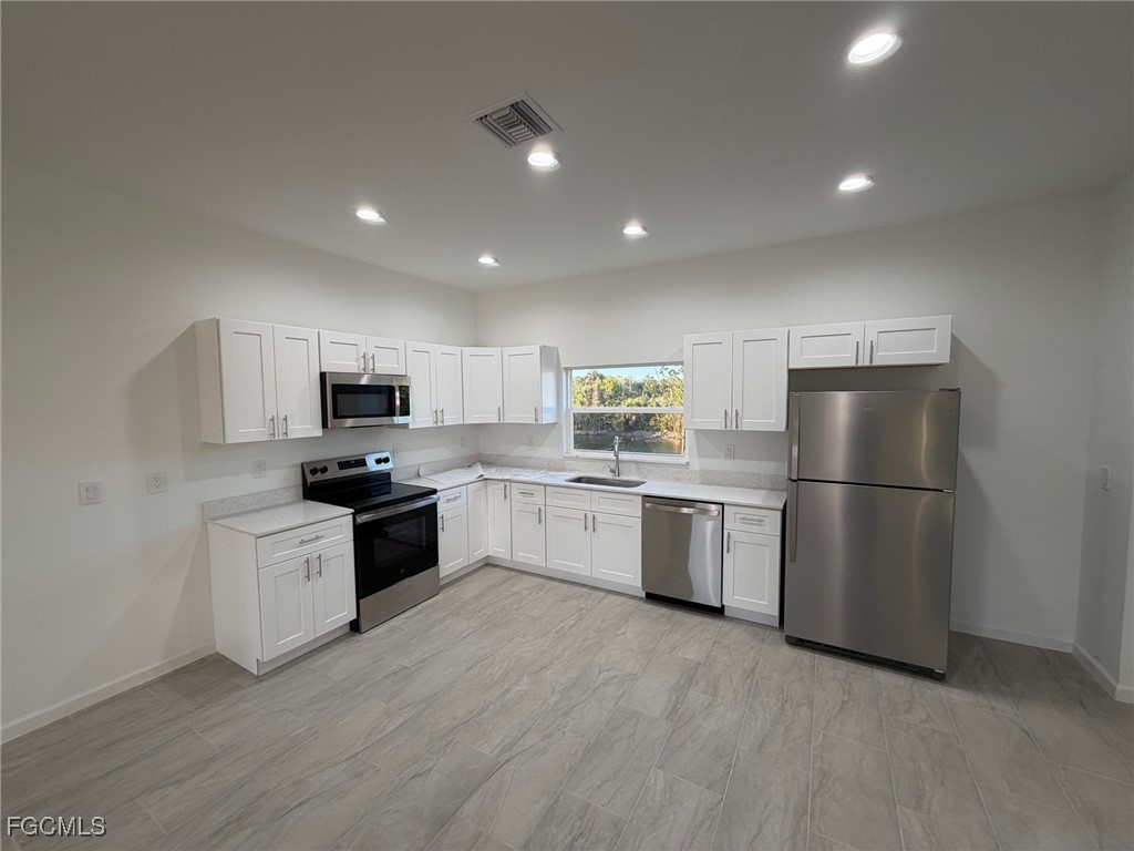 3307 10th Street Southwest Lehigh Acres, FL 33976 - Photo 3 of 13 a kitchen with a sink a counter top space stainless steel appliances and cabinets