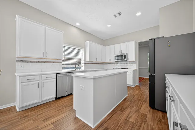 a view of a kitchen with kitchen island a appliances wooden cabinets and a sink