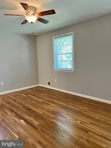 an empty room with wooden floor chandelier fan and windows