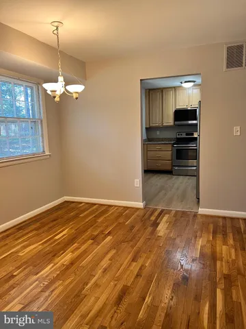 a view of empty room with wooden floor and ceiling fan