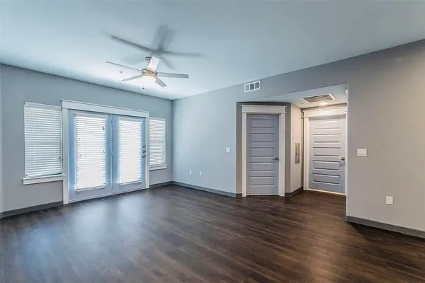 an empty room with wooden floor and windows