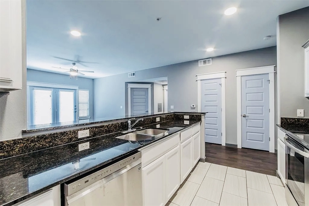 200 Maple Lane, Unit 1302 Elgin, TX 78621 - Photo 8 of 18 a large kitchen with granite countertop a sink and a stove top oven