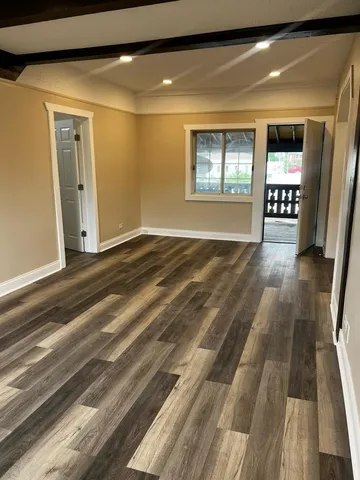 a view of an empty room with window and wooden floor