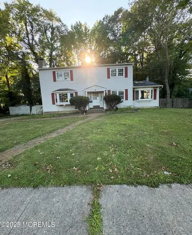a front view of a house with a garden and trees