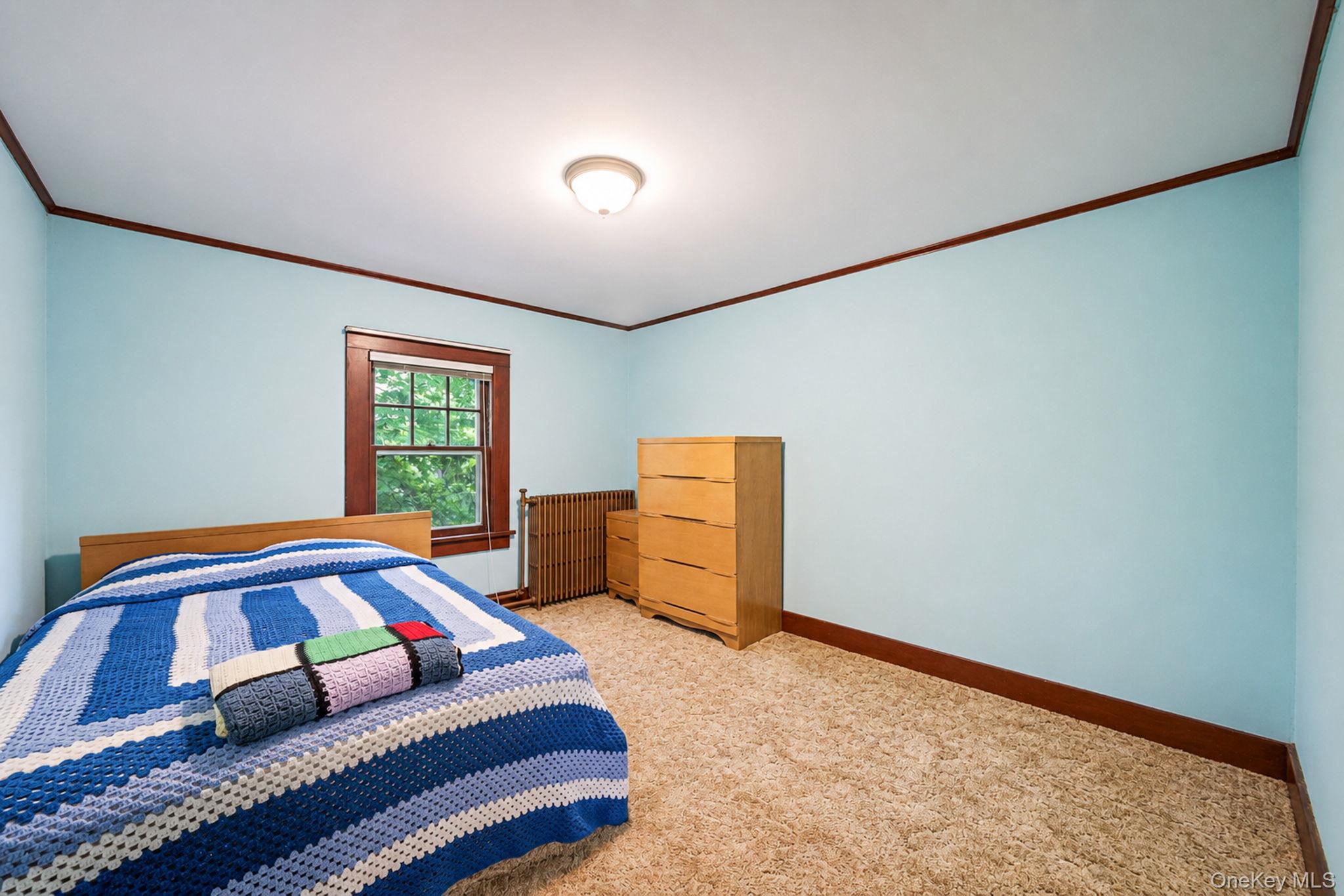 1055 Oregon Road Mattituck, NY 11952 - Photo 22 of 33 Carpeted room with a single window featuring wood trim. Wood floors under the carpeting.