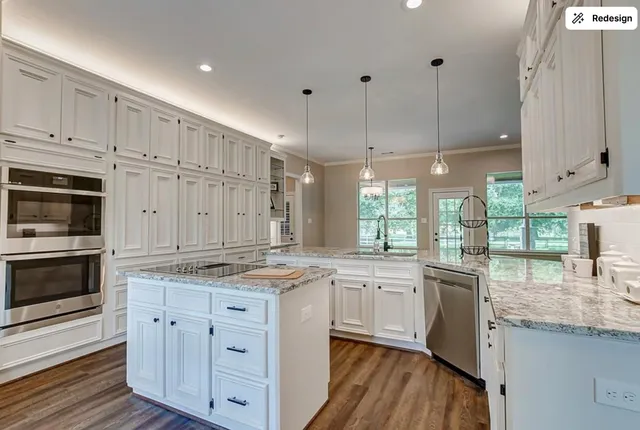 a kitchen with stainless steel appliances granite countertop a stove a sink and white cabinets with wooden floor