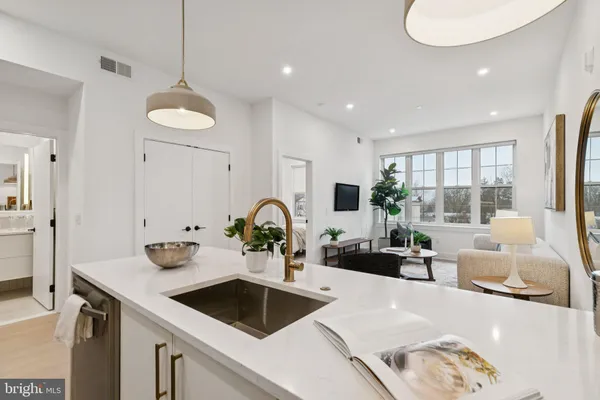 a kitchen with a sink a counter space and living room view