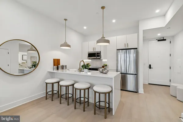 a kitchen with stainless steel appliances granite countertop a refrigerator a sink a stove and a wooden floor