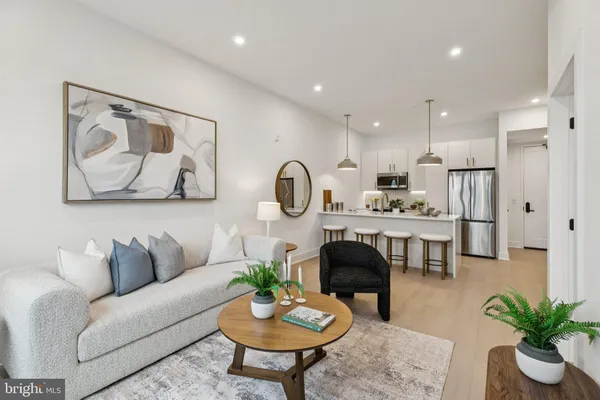a living room with furniture potted plant and kitchen view