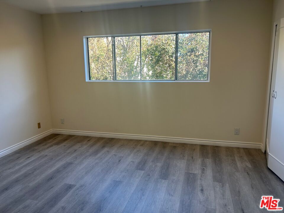 1440 Reeves Street, Unit 105 Los Angeles, CA 90035 - Photo 4 of 9 an empty room with wooden floor and windows