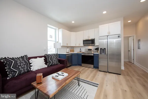 a kitchen with granite countertop a refrigerator a sink a stove a dining table and chairs