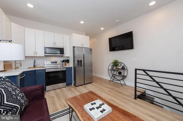 a living room with furniture a flat screen tv and a refrigerator
