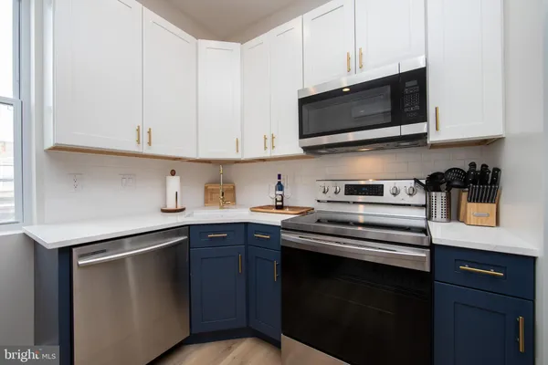 a kitchen with stainless steel appliances granite countertop a sink dishwasher a stove and a microwave oven on cabinets