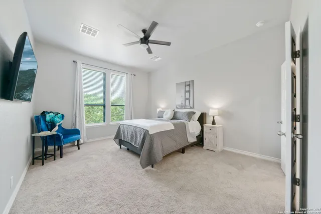 a spacious bedroom with a bed a window and a flat screen television