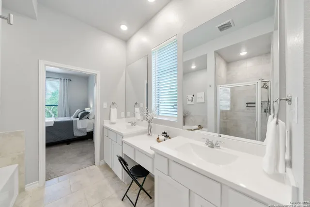 a en suite bathroom with a double vanity sink mirror and shower