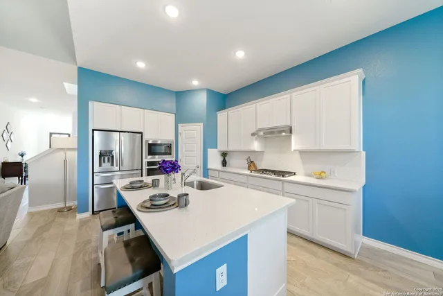 a kitchen with a sink a stove a refrigerator and white cabinets with wooden floor