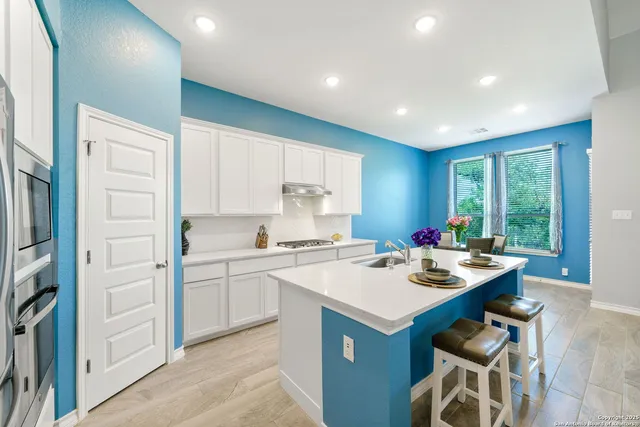 a kitchen that has a sink a stove and chairs