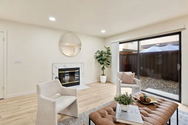 a living room with furniture a fireplace and a floor to ceiling window