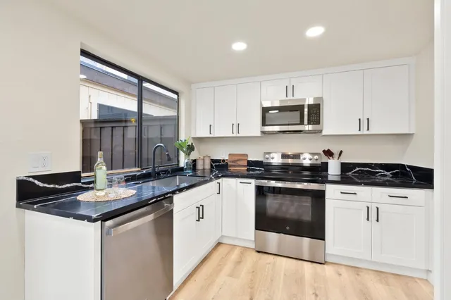 a kitchen with stainless steel appliances granite countertop a stove a sink and a microwave
