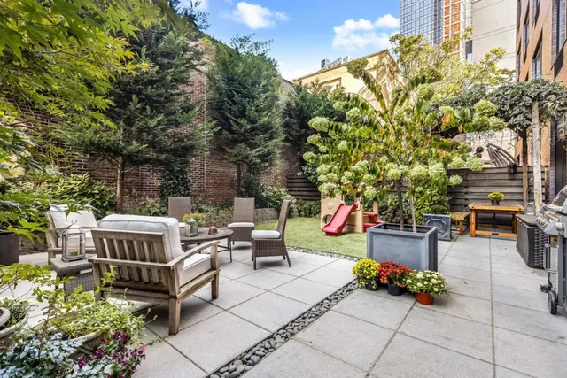 a view of a patio with table and chairs potted plants and large tree