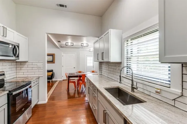 a kitchen with stainless steel appliances granite countertop sink stove top oven and cabinets