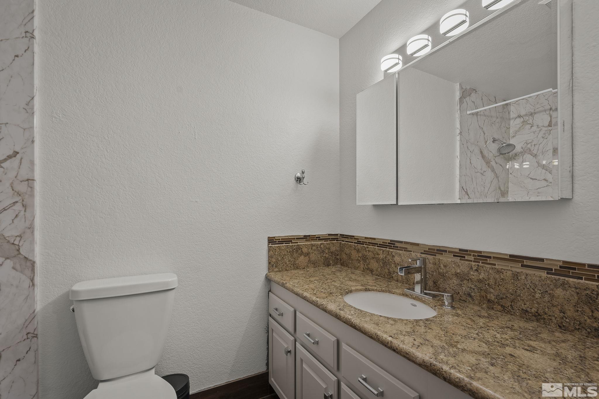 10890 Osage Road Reno, NV 89508 - Photo 20 of 40 a bathroom with a granite countertop sink a toilet and mirror