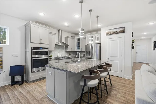 a kitchen with stainless steel appliances granite countertop a stove refrigerator a oven a sink and a dining table with wooden floor