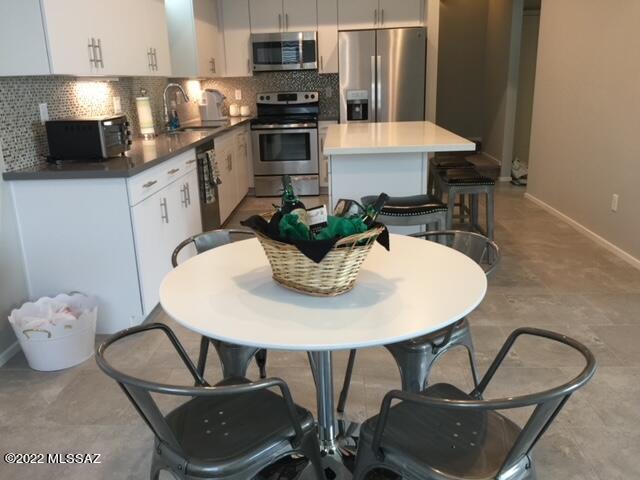 866 East Millenium Court Tucson, AZ 85719 - Photo 7 of 15 a kitchen with stainless steel appliances kitchen island granite countertop a sink a stove a dining table and chairs