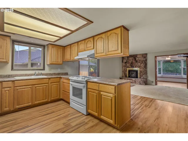 a kitchen with stainless steel appliances granite countertop a sink dishwasher stove and wooden cabinets