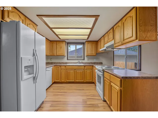 a kitchen with stainless steel appliances granite countertop a kitchen island a stove a sink a refrigerator and cabinets