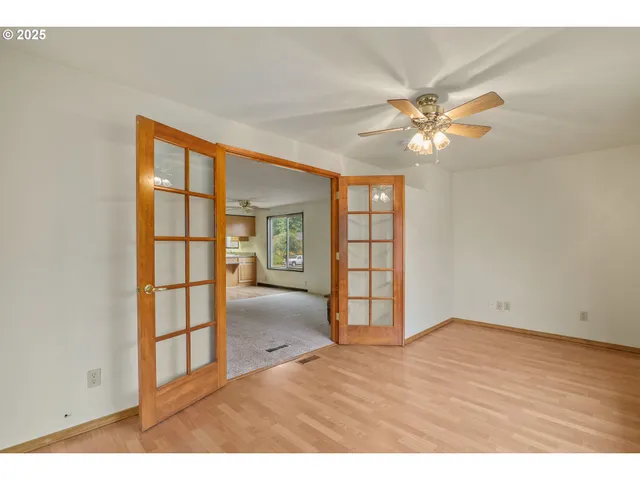 an empty room with wooden floor closet and windows