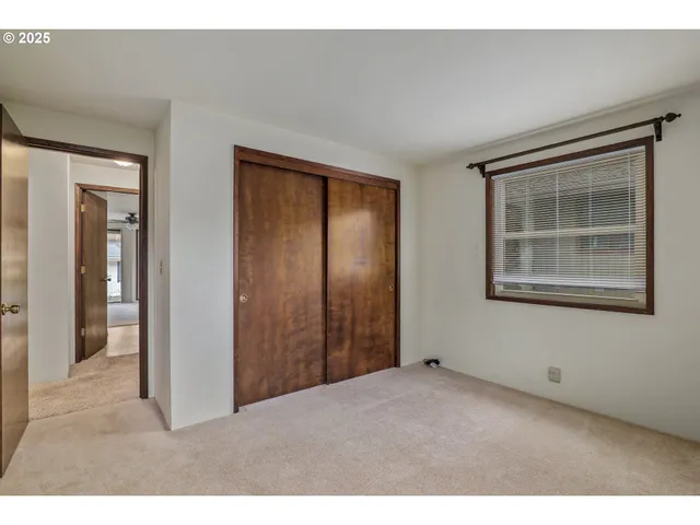 a view of an empty room with closet and a window