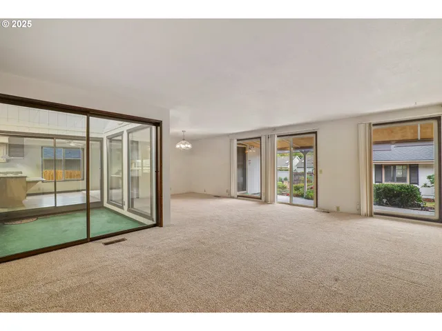 a view of an empty room with wooden floor and windows