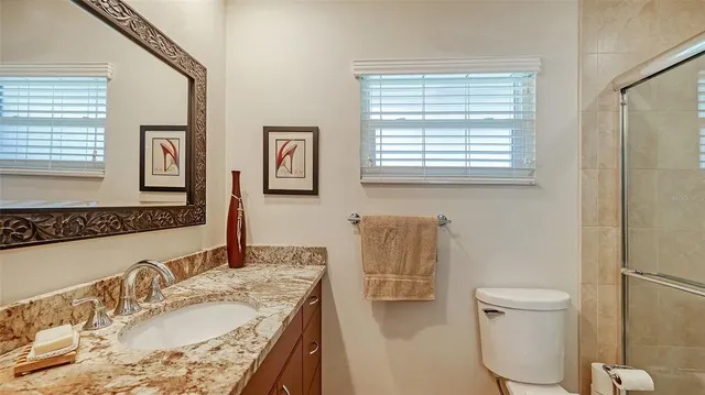 a bathroom with a granite countertop sink toilet and a mirror
