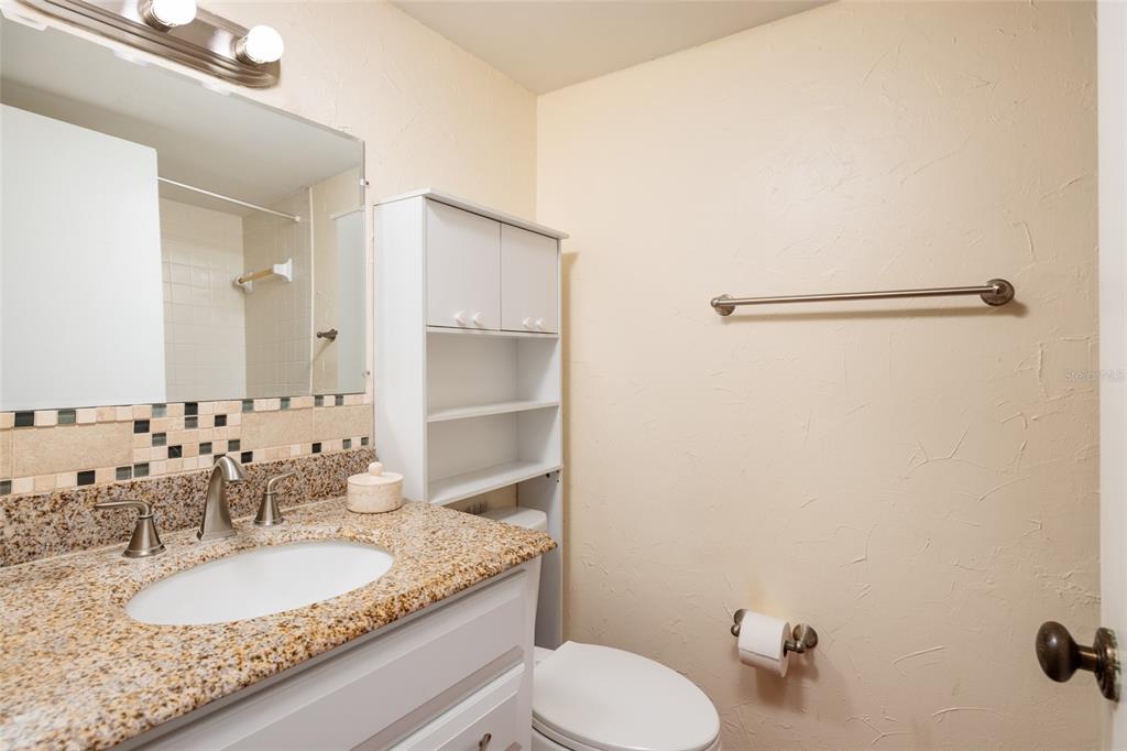 5409 Orange Blossom Road Pinellas Park, FL 33782 - Photo 17 of 30 a bathroom with a granite countertop sink toilet a mirror and shower