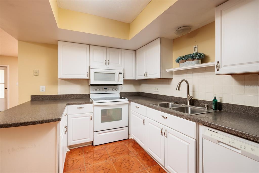 5409 Orange Blossom Road Pinellas Park, FL 33782 - Photo 5 of 30 a kitchen with granite countertop white cabinets and white appliances