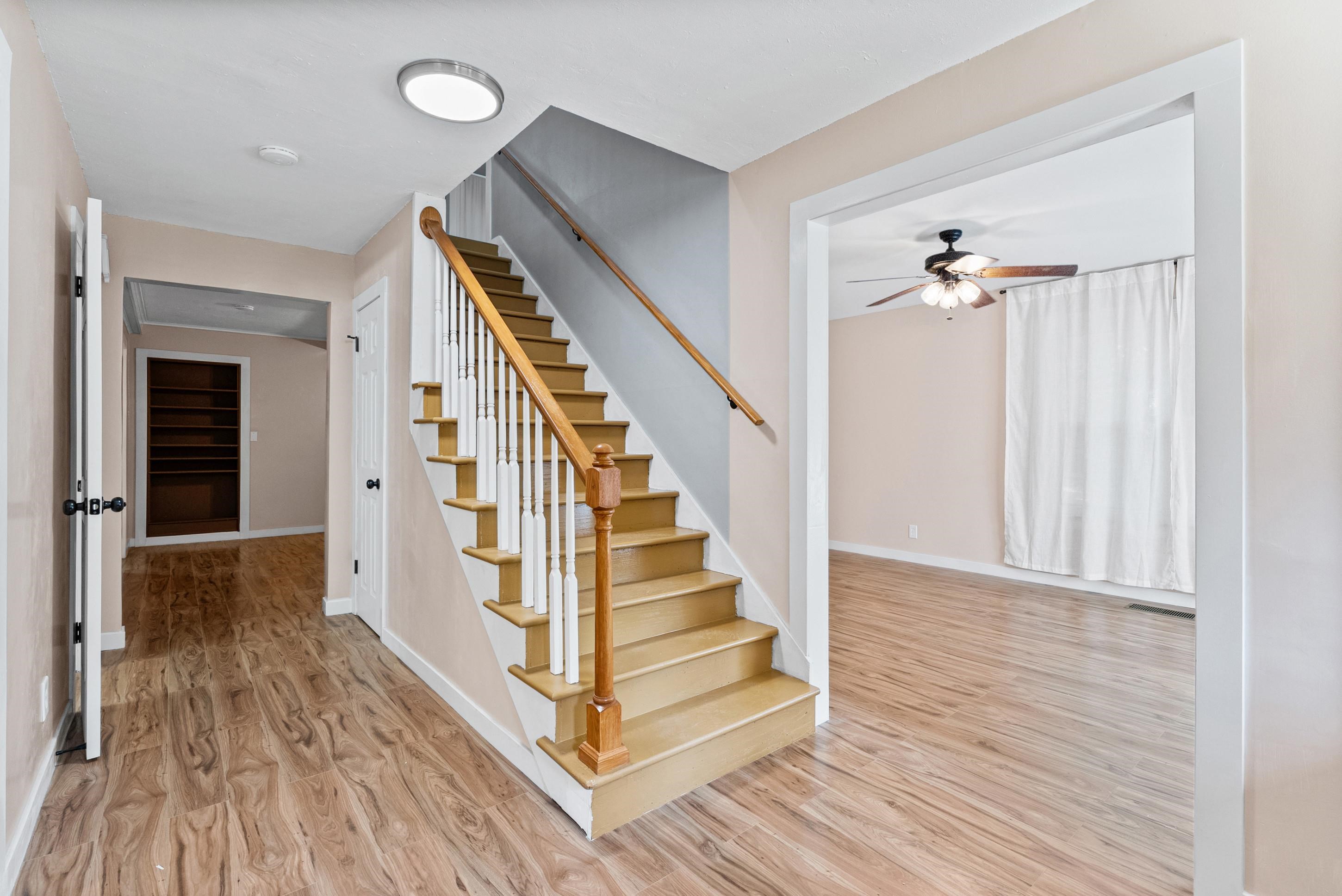 779 Strickland Road Coldwater, MS 38618 - Photo 4 of 40 Wood-finish flooring throughout, staircase with wood handrail and white balusters, recessed lighting, and a ceiling fan in the adjacent room