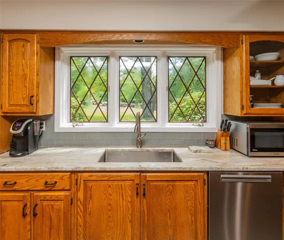 a kitchen with stainless steel appliances granite countertop a sink window and cabinets
