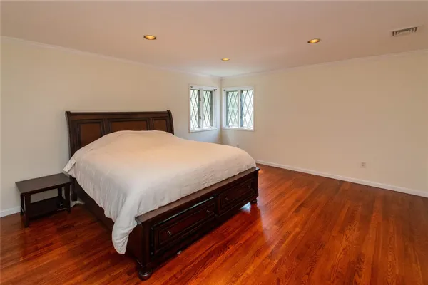 a bed sitting in a bedroom next to a window with wooden floor