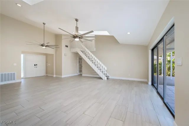 an empty room with wooden floor fan and windows