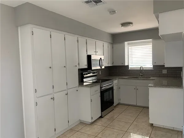 a kitchen with granite countertop white cabinets and stainless steel appliances