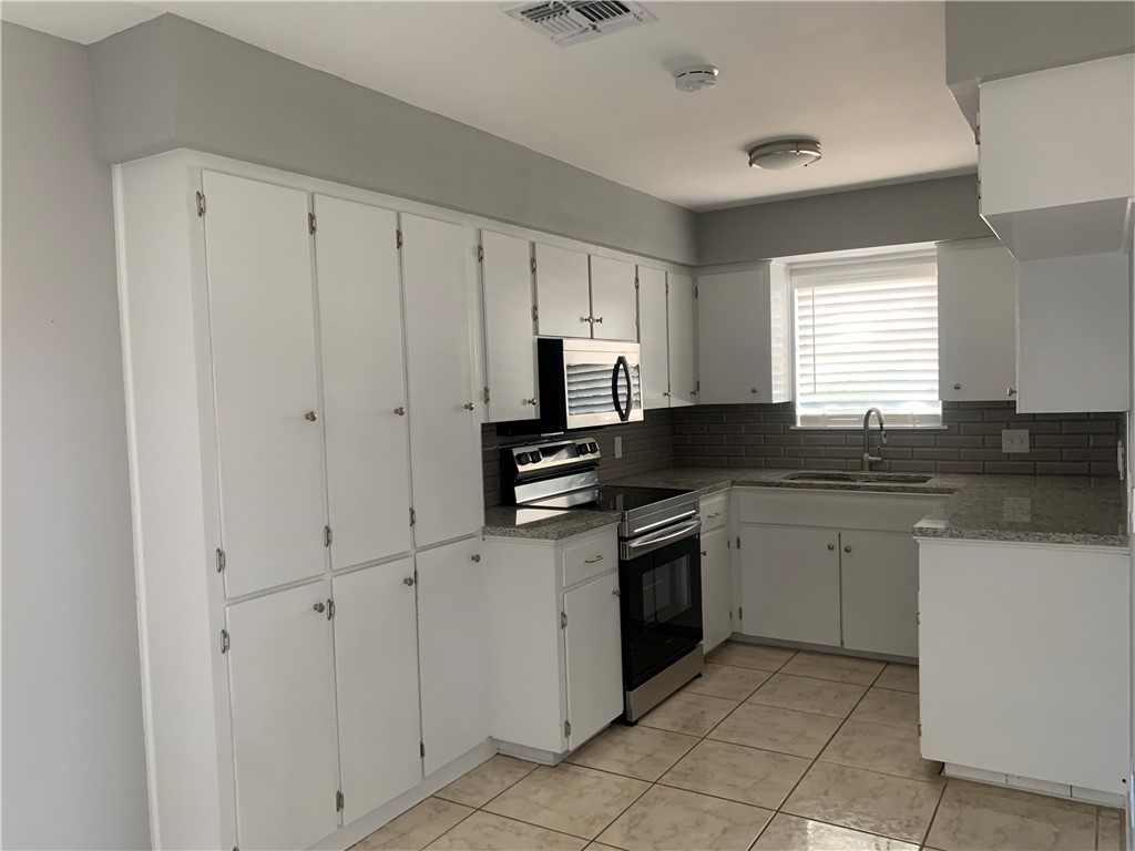1601 West Manor Drive Corpus Christi, TX 78411 - Photo 11 of 25 a kitchen with granite countertop white cabinets and stainless steel appliances