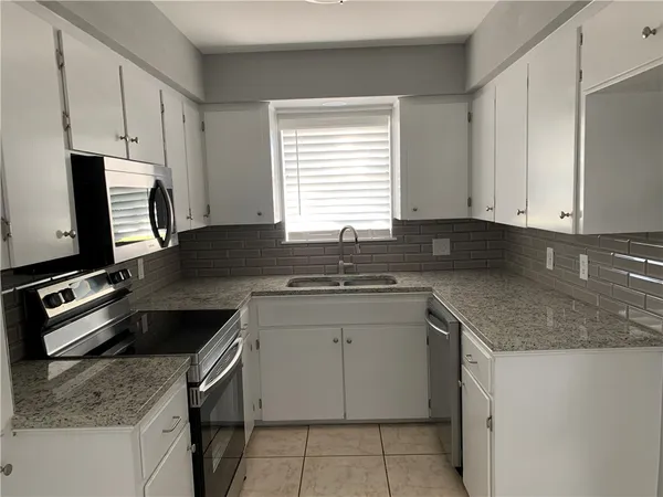 a kitchen with granite countertop a sink stove and cabinets