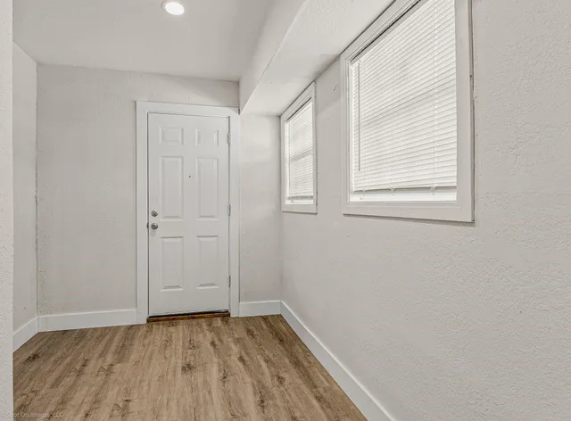 an empty room with wooden floor and windows