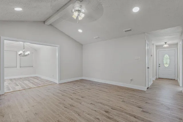 an empty room with wooden floor and a ceiling fan